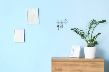 Mavi duvarda çekmeceleri ve anahtar tutacağı olan şık bir salonun içinde.