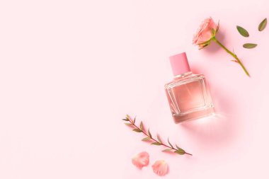 Pembe arka planda gül ve taç yaprakları olan bir şişe parfüm.