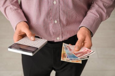Hesap makinesi ve banknotları elinde tutan bir erkek muhasebeci. Yakın çekim.