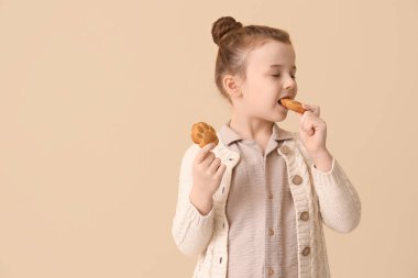 Bej arka planda kurabiye yiyen küçük kız.