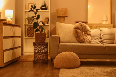 Konforlu kanepe, çekmeceler ve oturma odasının içinde parlayan lambalar.