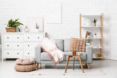 Oturma odasında kanepe, masa ve yeşil bitkiler var.