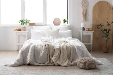 Konforlu yatağı, çiçekleri ve modern gardırobu olan aydınlık yatak odası.