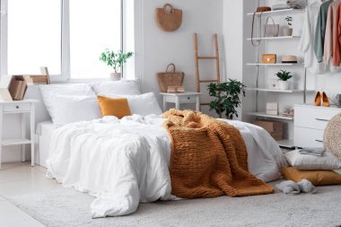 Konforlu yatağı, çiçekleri ve modern gardırobu olan aydınlık yatak odası.