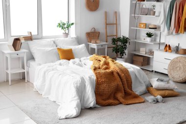 Konforlu yatağı, çiçekleri ve modern gardırobu olan aydınlık yatak odası.