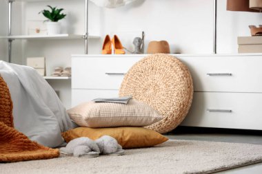 Yatak odasının içinde yastıklarda dergi, rahat yatak ve modern gardırop var.