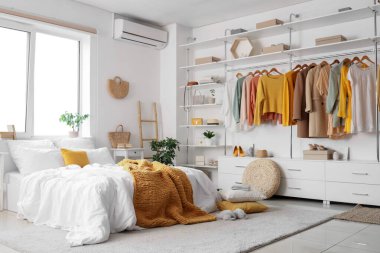 Konforlu yatağı, çiçekleri ve modern gardırobu olan aydınlık yatak odası.