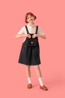 Pembe arka planda şık giyinmiş tatlı kızıl kız.