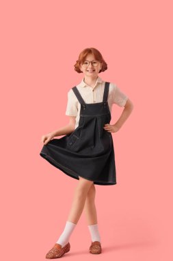 Şık giyinmiş, pembe arka planda gözlüklü tatlı kızıl kız.