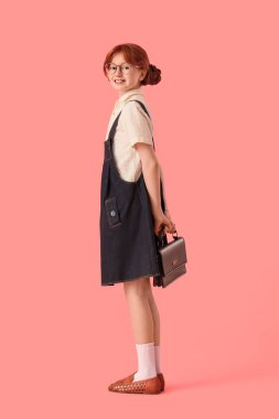 Pembe arka planda el çantası olan şık giyinmiş hoş bir kızıl kız.