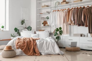 Işıl ışıl yatak odası, rahat yatak odası, hasır pouf dizüstü bilgisayar ve şık gardırop.