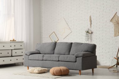 Depremden sonra dağınık oturma odasının içinde gri kanepe ve dağınık eşyalar var.