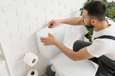 Erkek tesisatçı, tuvalette tuvalet depolarını tamir ediyor.