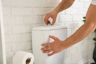 Erkek tesisatçı, tuvalette tuvalet depolarını tamir ediyor.