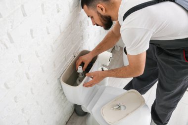 Erkek tesisatçı, tuvalette tuvalet depolarını tamir ediyor.