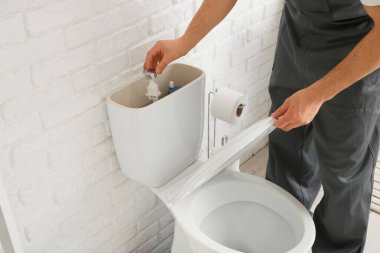 Erkek tesisatçı, tuvalette tuvalet depolarını tamir ediyor.