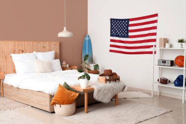 Yatak odasının içinde ABD bayrağı, sörf tahtası ve bank var.