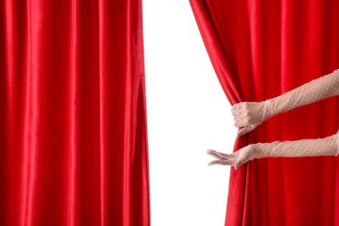 Beyaz arka planda kırmızı kadife perdeleri açan kadın elleri