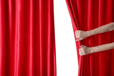 Beyaz arka planda kırmızı kadife perdeleri açan kadın elleri