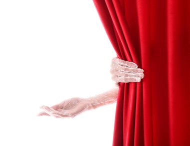 Kadın elleri beyaz arka planda açık kırmızı kadife perdelerin arkasından bir şey gösteriyor.