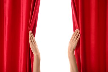 Beyaz arka planda kırmızı kadife perdeleri açan kadın elleri