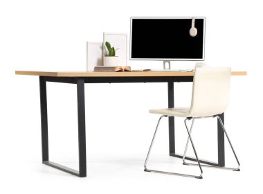 Beyaz arka planda modern bilgisayar ve ev bitkisine sahip şık çalışma alanı