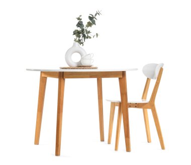 Beyaz arka planda okaliptüs dalları ve sandalyeli şık bir yemek masası.