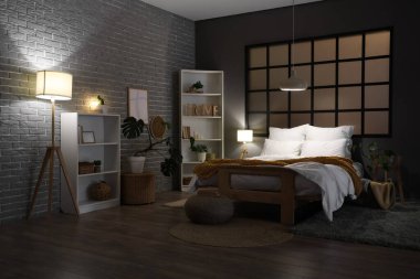 Şık bir yatak odası, rahat bir yatak odası, raf üniteleri ve akşam lambaları.