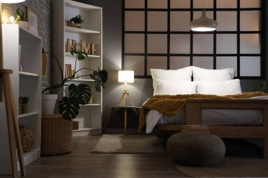 Şık bir yatak odası, rahat bir yatak odası, raf üniteleri ve akşam lambaları.