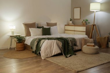 Şık bir yatak odası, rahat bir yatak odası, çiçekler ve akşam lambaları.