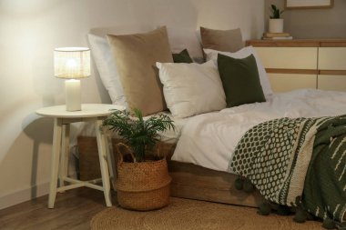 Şık bir yatak odası. Yatağı ve gece yatağının yanındaki lamba parlıyor.