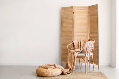 Şık bir oturma odası, rahat koltuk, hasır puf ve katlanır ekran.