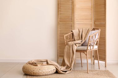 Şık bir oturma odası, rahat koltuk, hasır puf ve katlanır ekran.