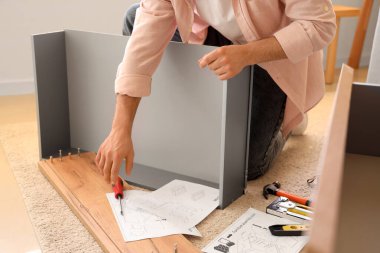 Tornavidalı bir adam çekmeceleri evde monte ediyor.