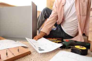 Mobilya planı olan bir adam evde çekmece montajı yapıyor.