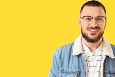 Sarı arka planda gözlüklü yakışıklı bir genç.