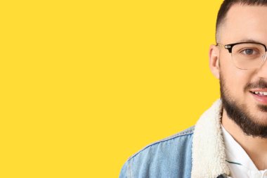 Sarı arka planda gözlüklü yakışıklı bir genç.