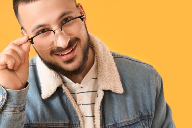 Sarı arka planda gözlüklü yakışıklı bir genç.