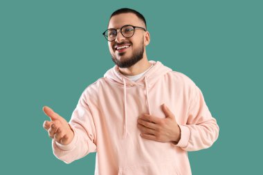 Minnettar genç adam göğüs göğüse verip yeşil arka planda gülümsüyor.