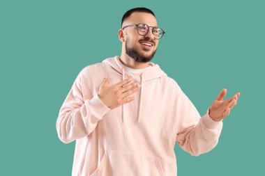 Minnettar genç adam göğüs göğüse verip yeşil arka planda gülümsüyor.