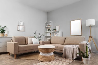 Modern oturma odasının içinde şık gri koltuklar, kahve masası ve ev bitkileri var.