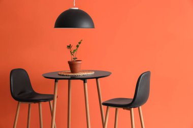 Oturma odasının içindeki turuncu duvara yakın masa ve sandalyeler, yakın plan.