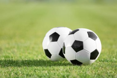 Yeşil stadyum çimlerinde futbol topları, yakın plan.