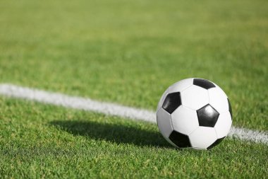 Yeşil stadyum çimlerinde futbol topu, yakın plan.