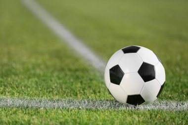 Yeşil stadyum çimlerinde futbol topu, yakın plan.