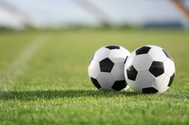 Yeşil stadyum çimlerinde futbol topları, yakın plan.