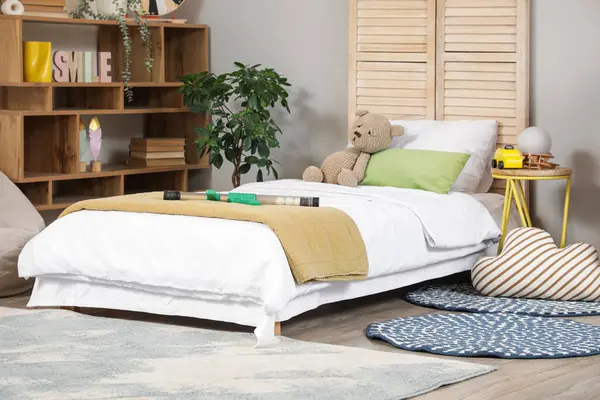 İçinde yatak, raf ünitesi ve oyuncaklar olan çocuk odası.