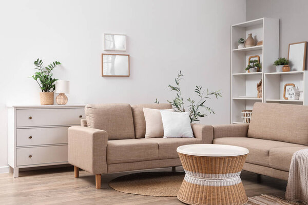 Interior of modern living room with stylish grey sofas, coffee table and houseplants