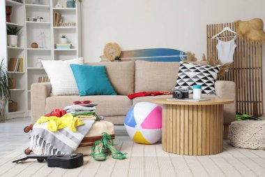 Oturma odasının içinde kanepe, bavul ve plaj aksesuarları var.