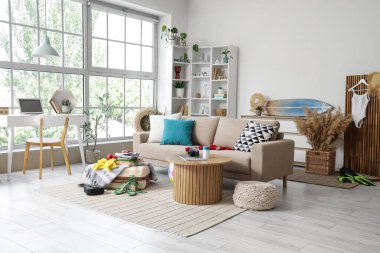 Oturma odasının içinde kanepe, bavul ve plaj aksesuarları var.